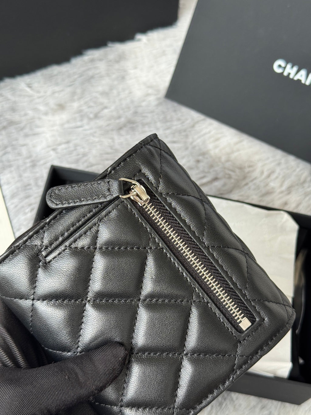 Black quilted small bag with top zipper and stitched diamond pattern