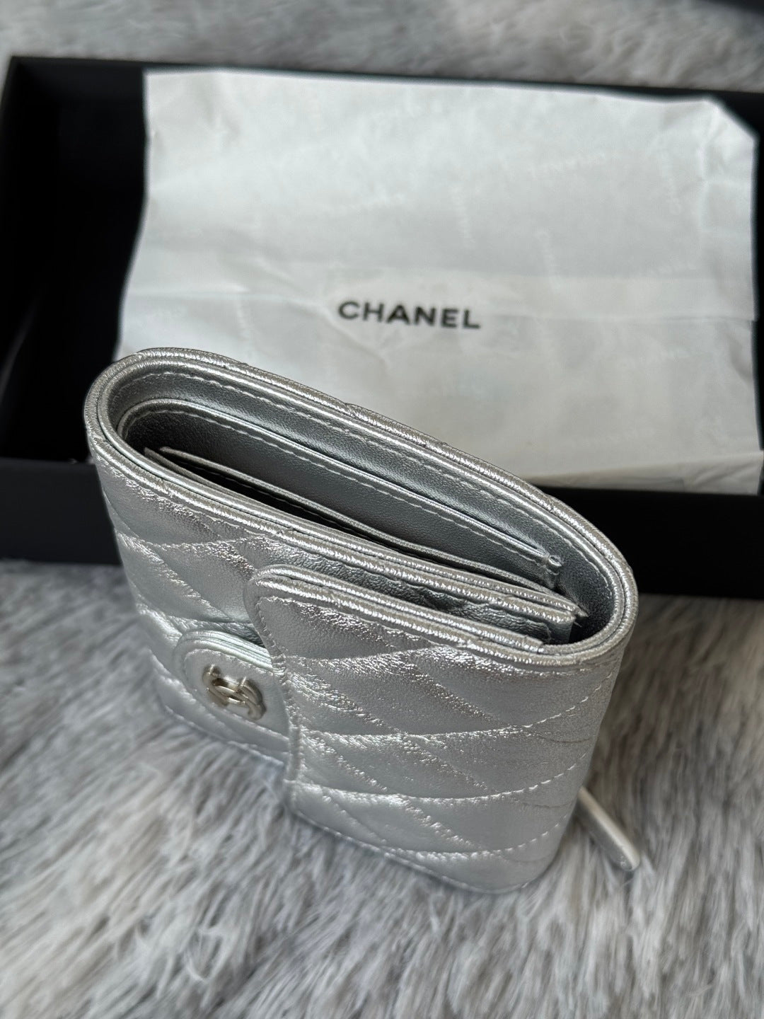 Chanel silver quilted wristlet bag detail with rolled zipper closure and ring tab.