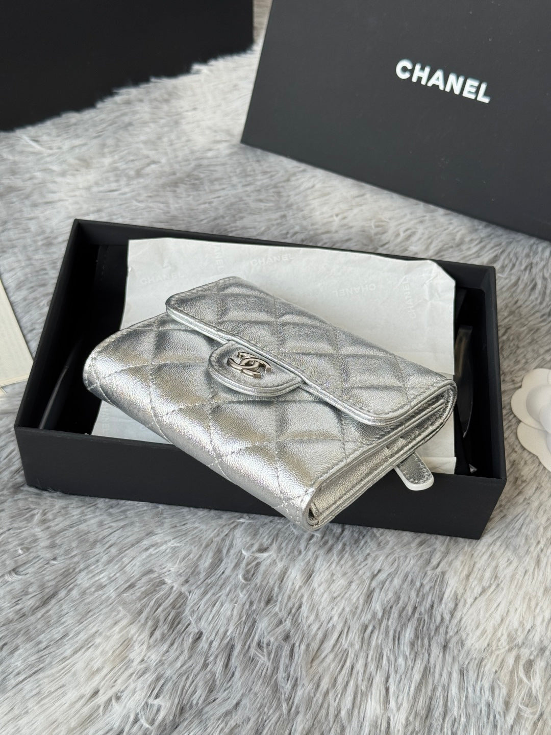 Chanel small silver quilted wristlet bag with top handle and flap clasp.