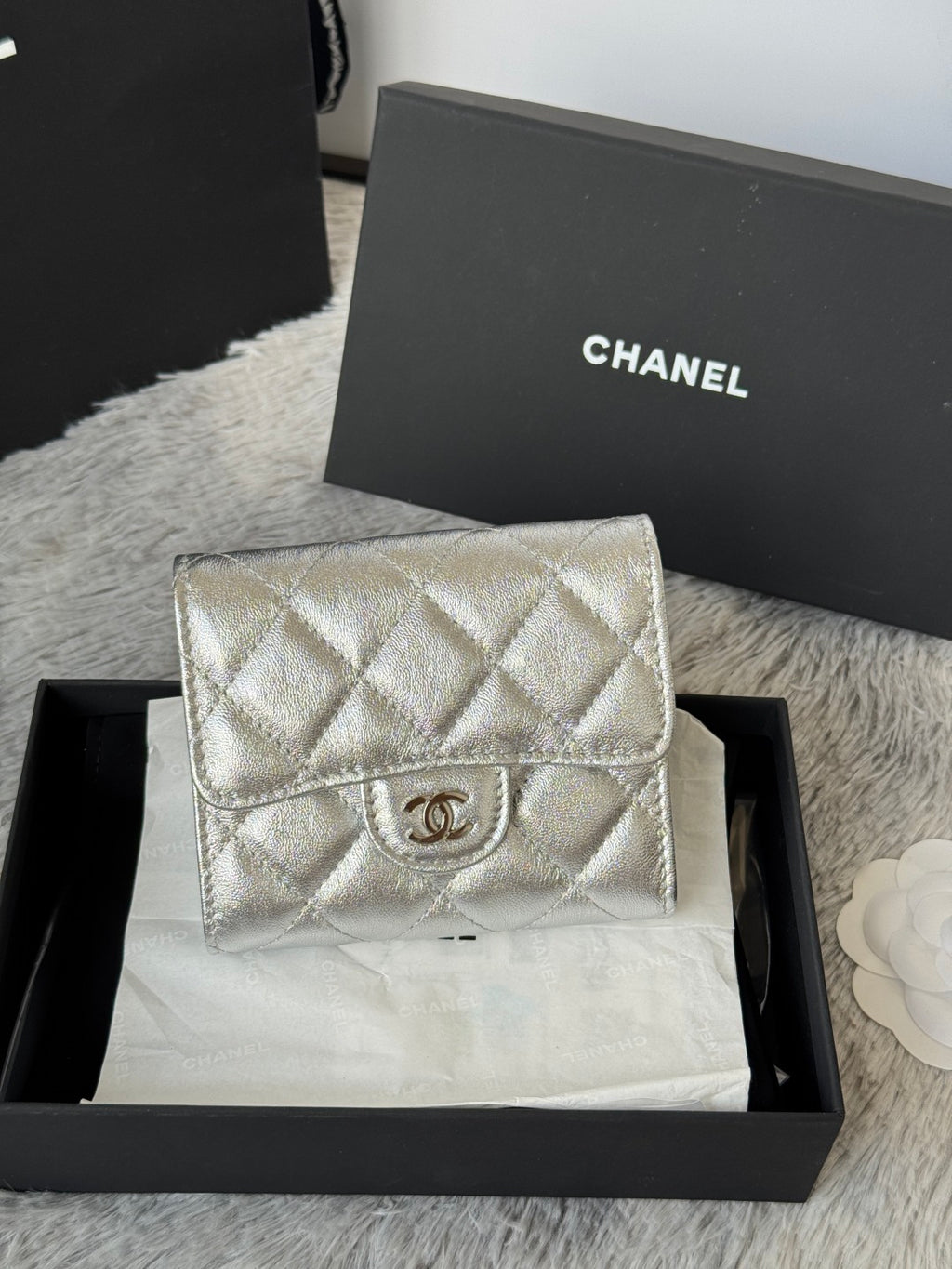 Chanel small silver quilted flap bag with CC logo on front.