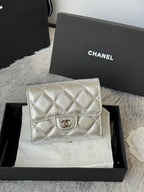 Chanel small silver quilted flap bag with CC logo on front.
