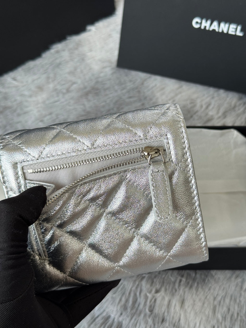 Chanel small silver quilted bag with open zipper top and interior pocket.