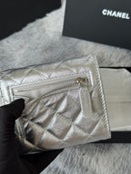 Chanel small silver quilted bag with open zipper top and interior pocket.