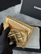 Chanel small gold quilted mini bag held by hand, showing interior zipper pocket