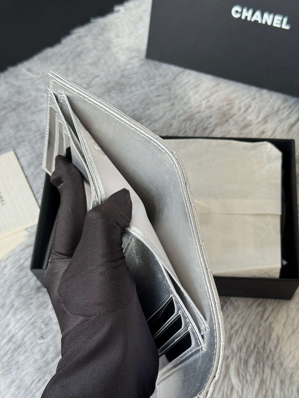Small silver bag with flap open, showing interior and side pocket