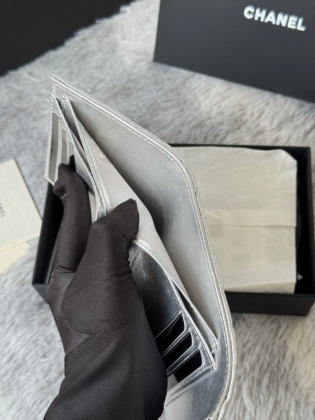 Small silver bag with flap open, showing interior and side pocket