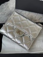 Chanel small silver quilted crossbody bag with CC logo on front flap.