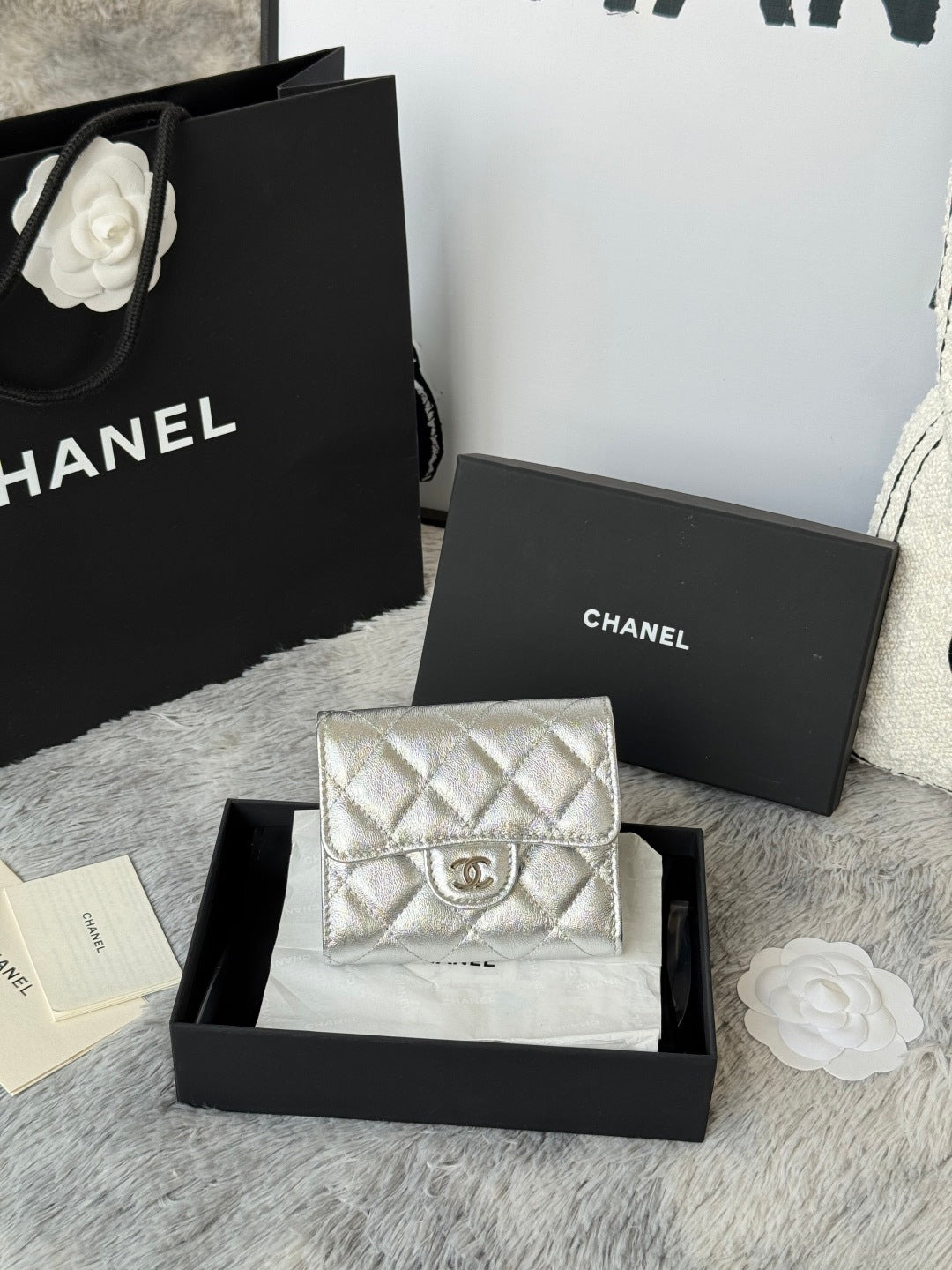 Chanel small silver quilted flap bag with chain strap, front logo medallion.