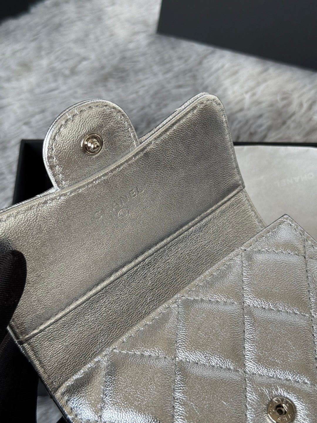 Small bag in metallic silver with snap-button flap and quilted front detail