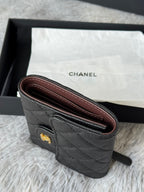 Small bag side view in dark quilted leather with burgundy interior lining and wrist strap.
