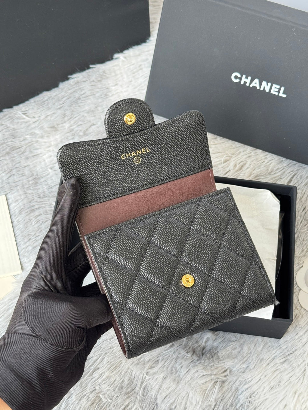 Small bag set: dark quilted leather with brown trim, snap button, and small gold CHANEL logos.