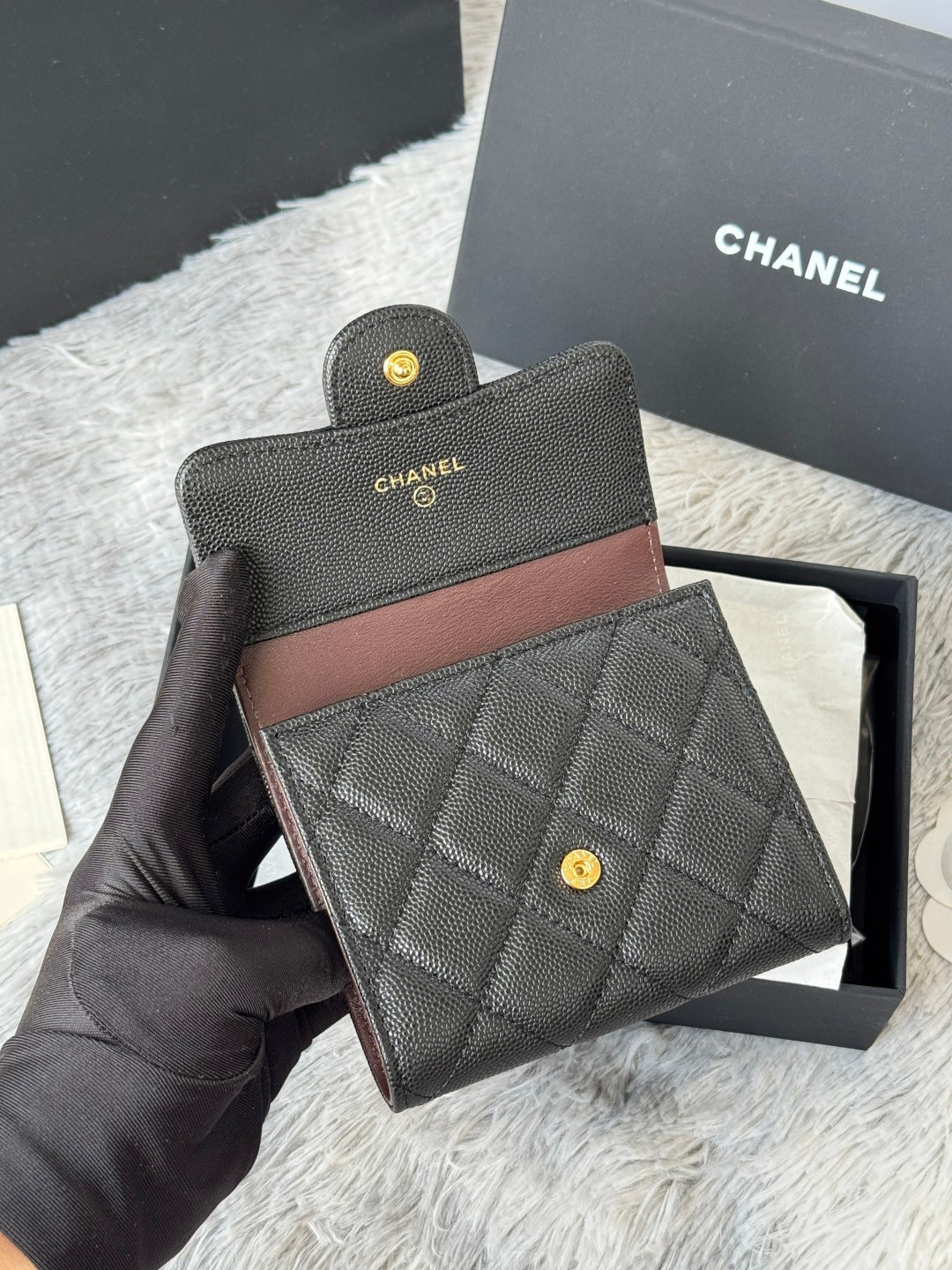Small bag set: dark quilted leather with brown trim, snap button, and small gold CHANEL logos.