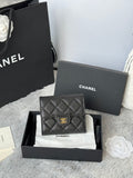Small bag with quilted black leather, flap closure, and gold CHANEL emblem hardware.