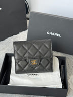 Small bag in dark quilted leather with front flap and gold CHANEL emblem on clasp.