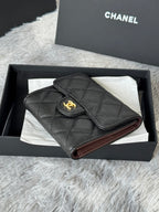 Small bag with quilted dark leather, flap top, and gold CHANEL emblem; burgundy lining.