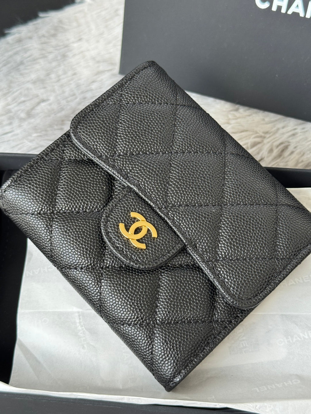 Small bag close-up: quilted dark leather with flap, raised edge stitching, and gold CHANEL logo.