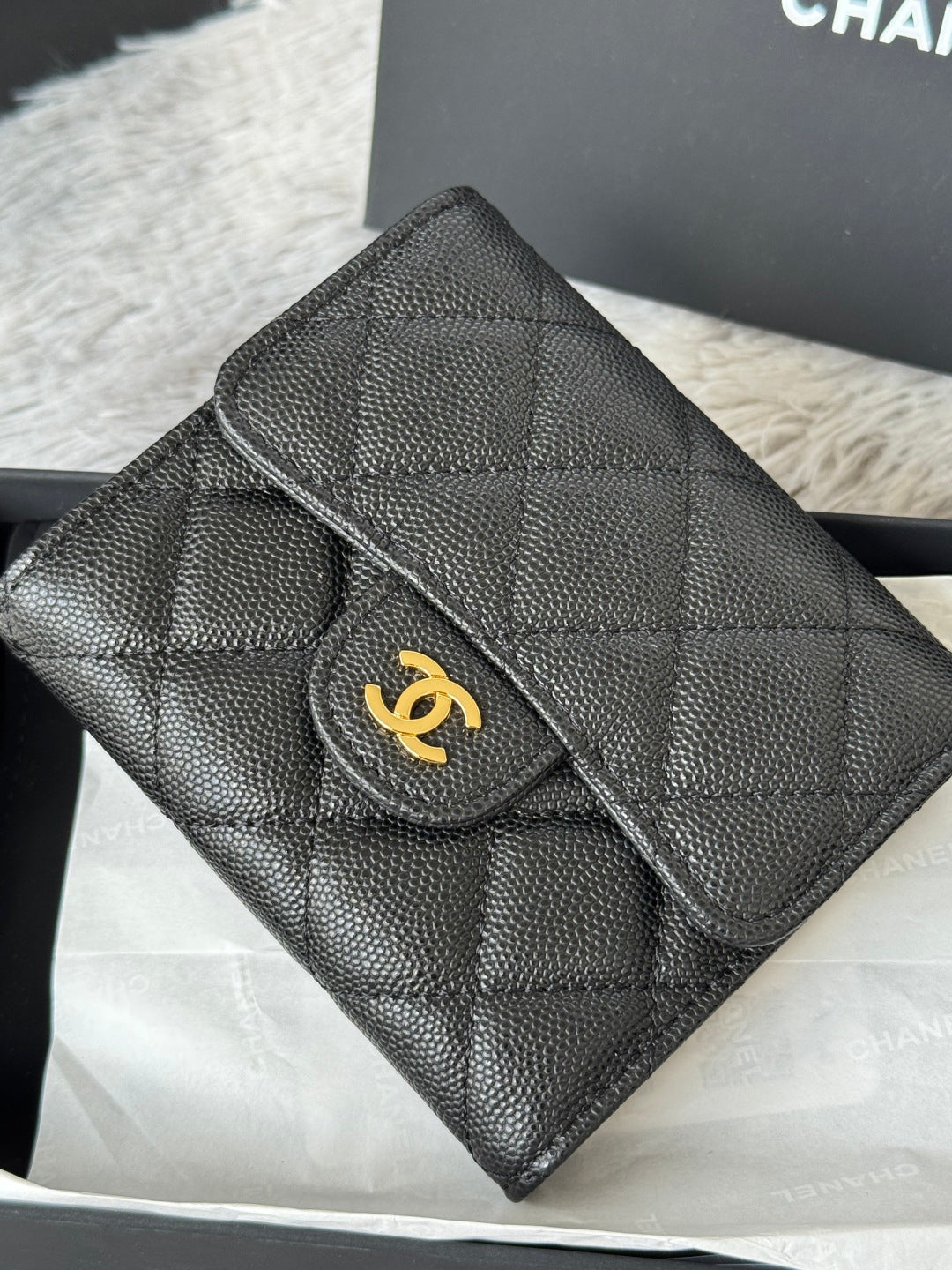 Small bag close-up: quilted dark leather with flap, raised edge stitching, and gold CHANEL logo.