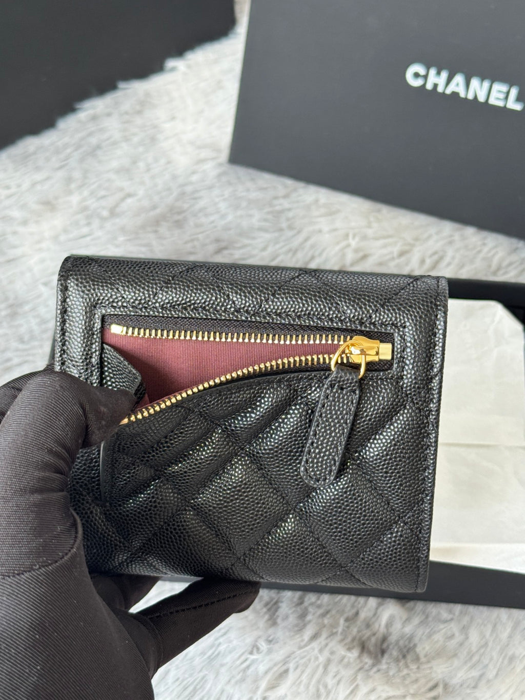 Small bag with flap open to show top zip; quilted dark leather and gold CHANEL hardware.