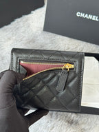 Small bag with flap open to show top zip; quilted dark leather and gold CHANEL hardware.