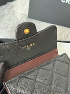 Small bag close-up: textured dark leather with brown stripe and gold CHANEL logo buttons.
