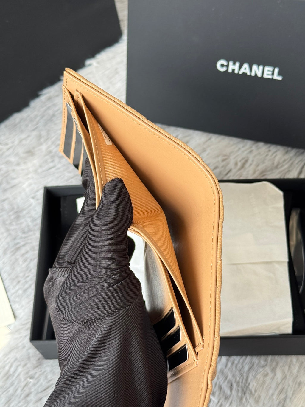 Tan leather small bag with open top and interior pocket, held by hand, CHANEL logo