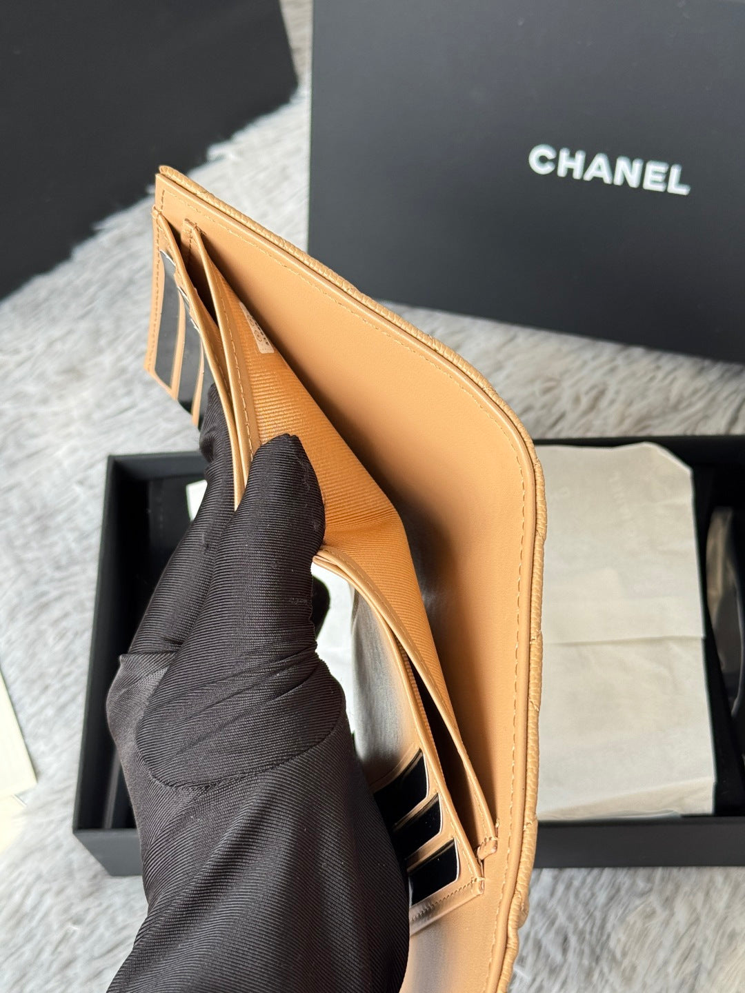 Tan leather small bag with open top and interior pocket, held by hand, CHANEL logo