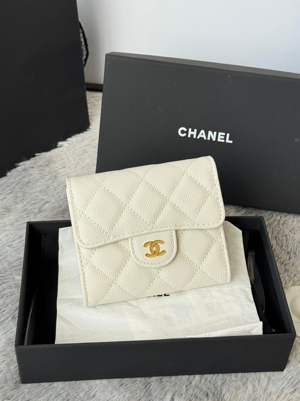 Off-white quilted flap bag with gold Chanel logo clasp, angled front view.