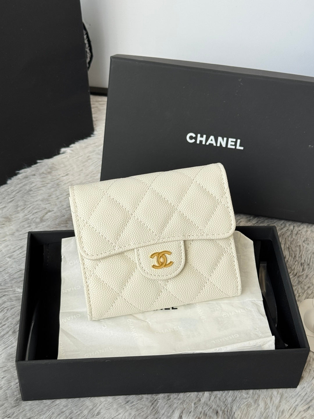 Off-white quilted flap bag with gold Chanel logo clasp, angled front view.
