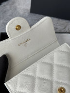 Off-white quilted mini bag with gold Chanel logo button, top corner close-up.