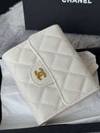 Off-white quilted mini bag with gold Chanel logo and flap detail, close-up angle.