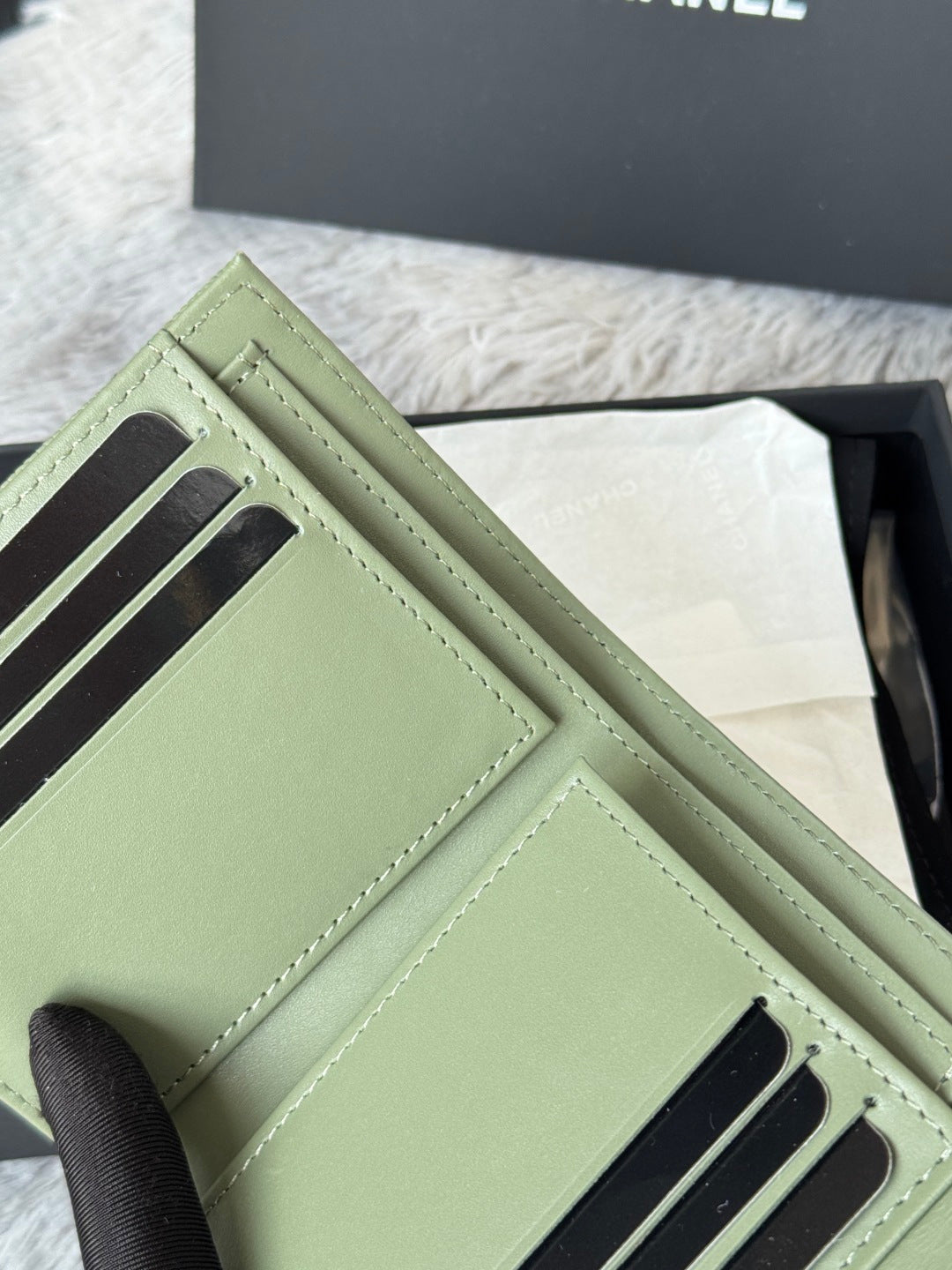 Small light green card holder pouch with black stripe slots and CHANEL logo