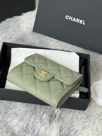 Small light green quilted flap bag with CHANEL logo button and wrist strap