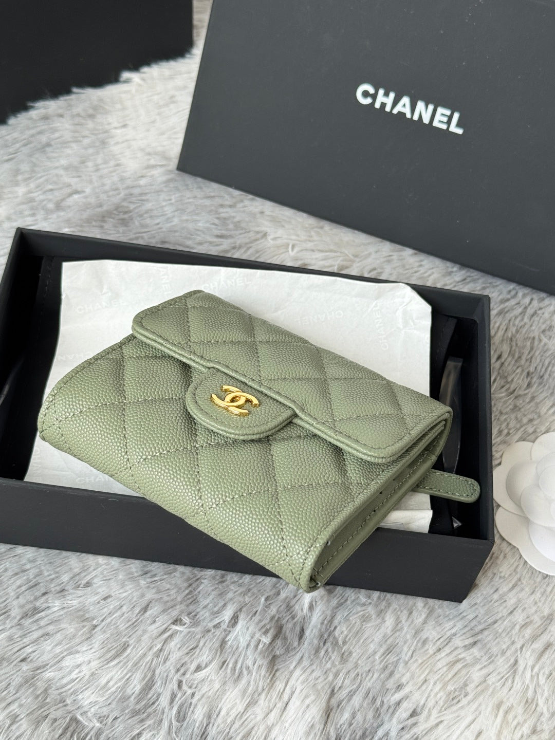 Small light green quilted flap bag with CHANEL logo button and wrist strap