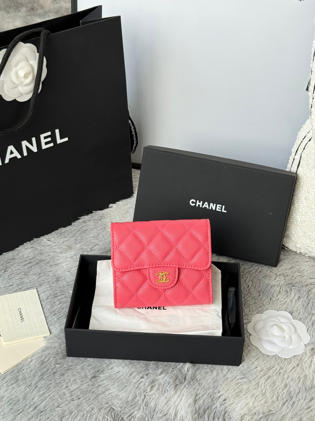 Pink quilted flap bag with gold CC logo, shown in black gift box