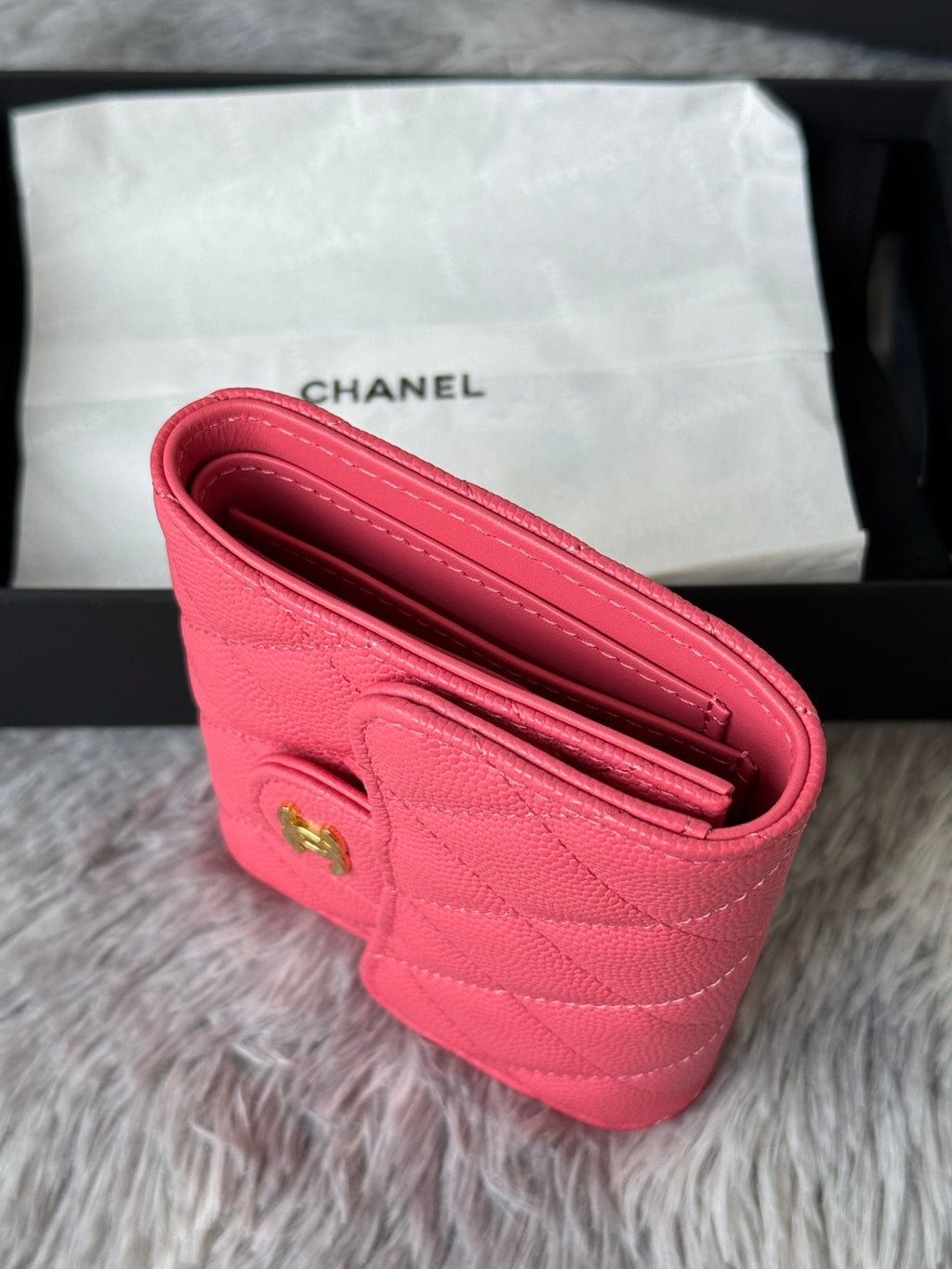 Pink quilted flap bag with open interior and stitched edges, gold snap hardware