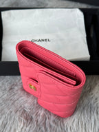 Pink quilted flap bag with open interior and stitched edges, gold snap hardware