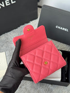 Pink quilted flap bag with gold CC button clasp, held in black-gloved hand