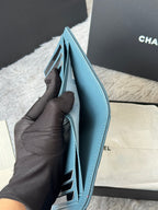 Open light blue small bag with inner card slots, held in gloved hand