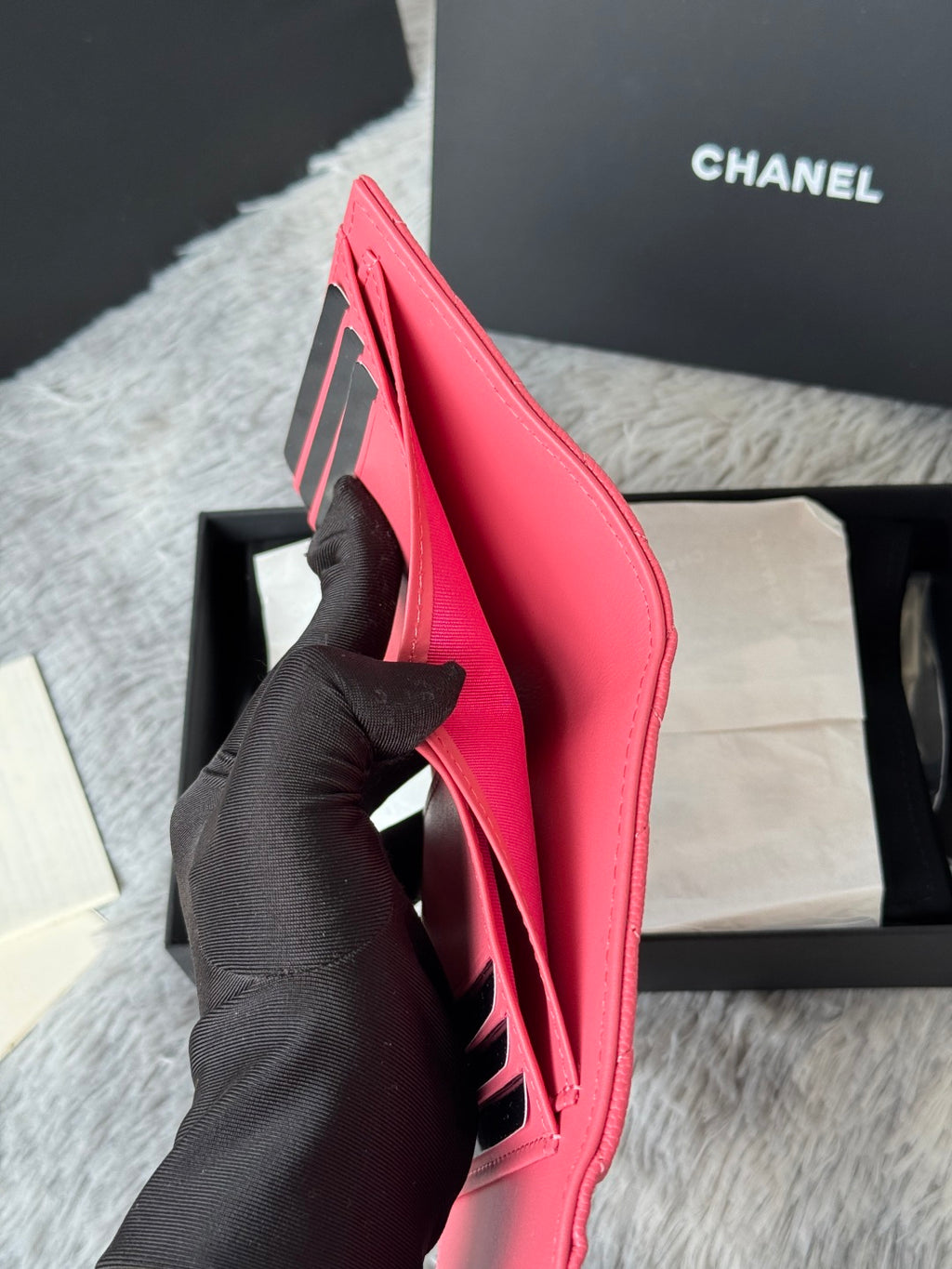Small pink Chanel bag side view with open pocket and black logo stripe