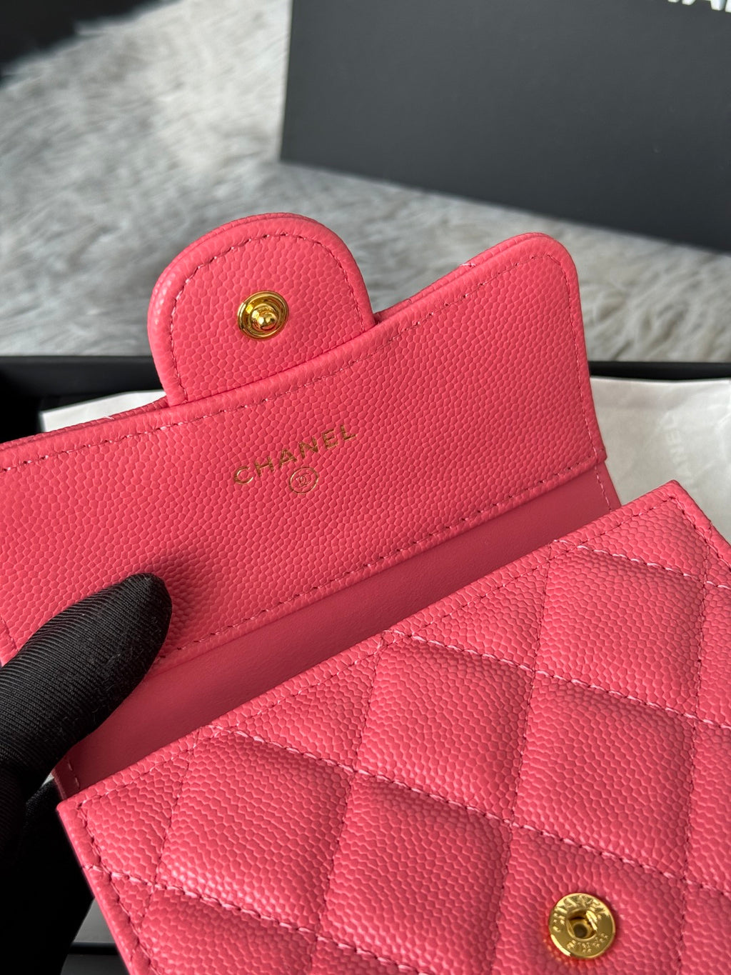 Pink quilted flap bag with gold CC button clasp, close-up