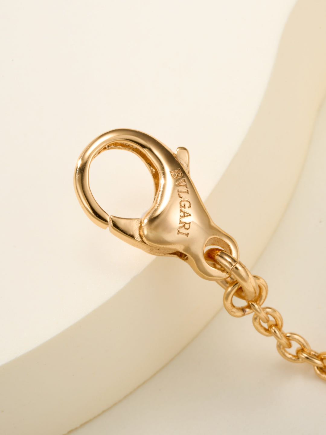 Gold clasp charm with engraved BVLGARI letters and attached chain link