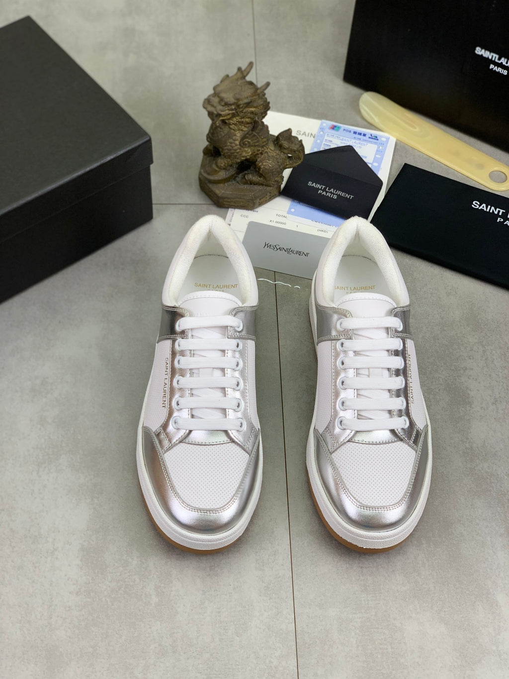 Pair of white low-top sneakers with white laces and metallic toe panels.