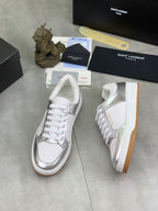 Side view of white low-top sneakers with silver inserts and white laces.