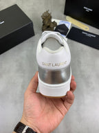 Back view of white and silver low-top sneakers with "SAINT LAURENT" on heel.