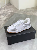 White low-top sneakers with metallic side panels, white laces, on black shoebox.