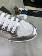 Close-up of white low-top sneaker toe with silver trim and white lace eyelets.