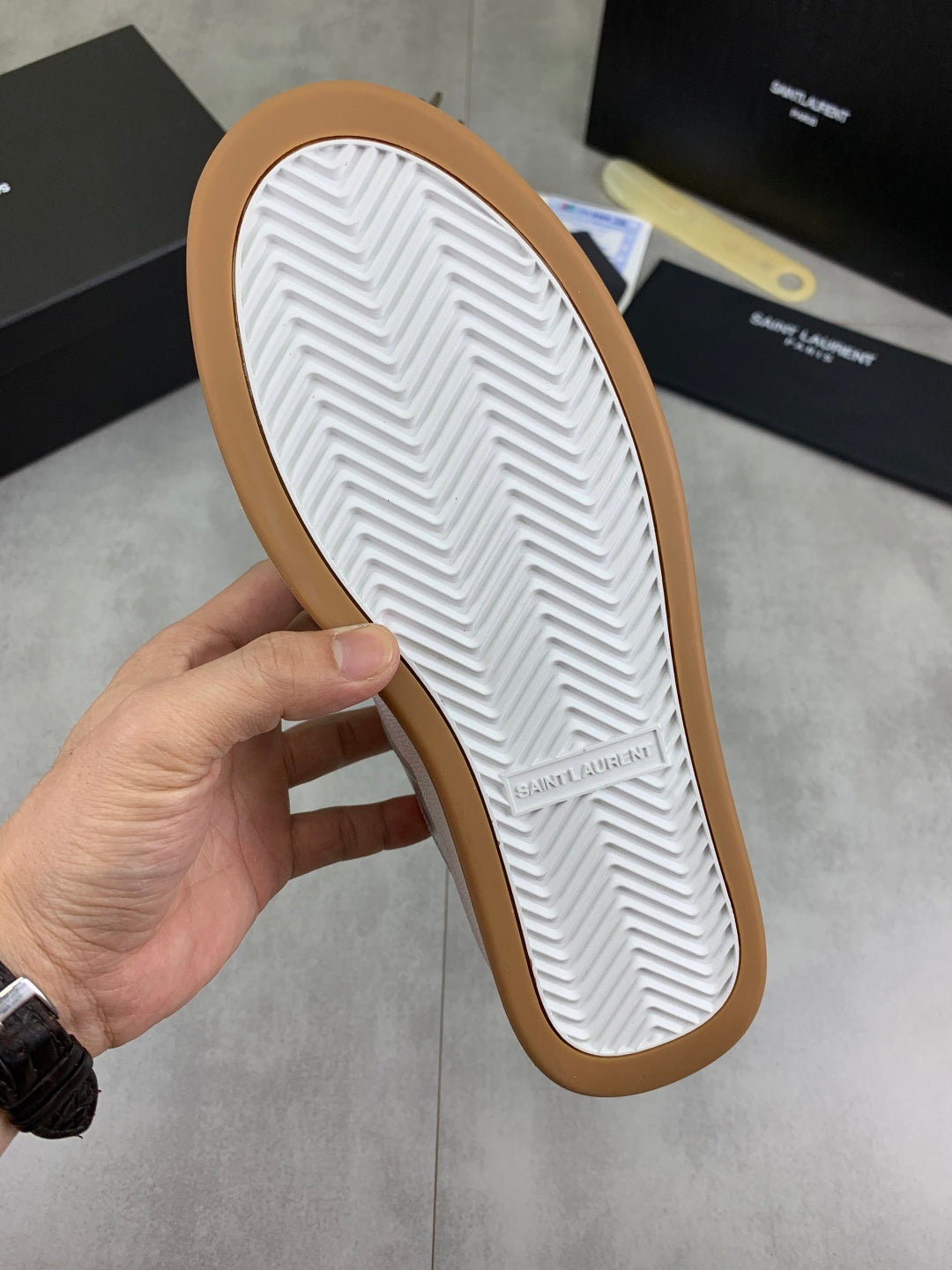 White sneaker outsole with zigzag tread and tan rubber edge border.
