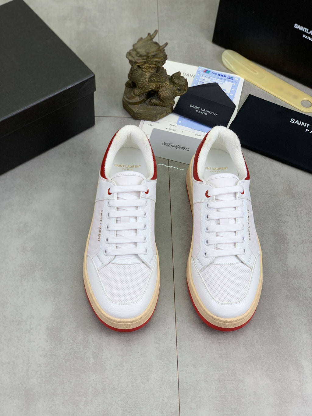 Pair of white lace-up sneakers with red collar accents and gum rubber soles.