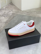 White low-top sneaker with red heel collar and gum rubber sole.