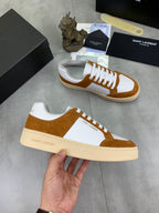 Brown suede and white sneakers in hand, white laces and off-white sole trim.